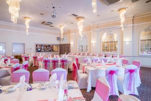 纽波特百汇温泉大酒店 的宴会厅配有白色桌子和粉红色椅子