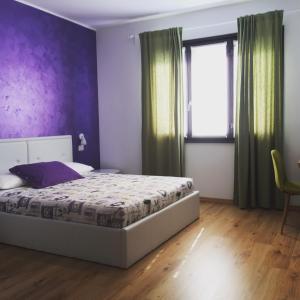 阿罗纳Il Gatto Stanco B&B的一间卧室配有一张床和紫色的墙壁