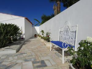 AroeiraCasa da Horta的坐在白色墙壁旁的石头走道上的长凳