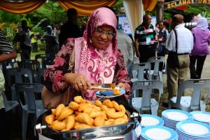 Kampong Jawa珊迪卡假日公园的把食物托盘放在桌子上的女人