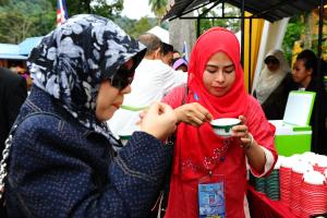 Kampong Jawa珊迪卡假日公园的两个头巾的女人从碗里吃食物