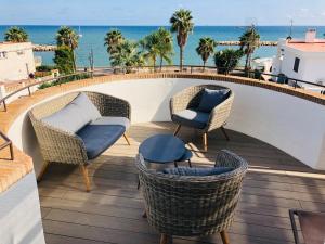 坎布里尔斯Casa Acacia Mar的阳台配有柳条椅和桌子,享有海景。