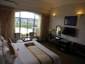 Kon Tum (2)Indochine Hotel的酒店客房配有一张床、一张书桌和一台电视。