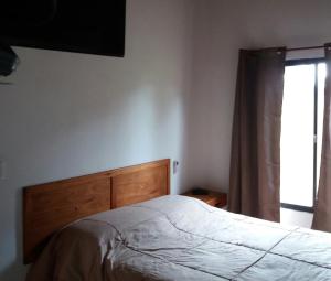 塔夸伦博La Araucana的一间卧室配有一张带木制床头板的床和窗户。