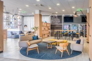 马德里Madrid Airport Suites, Affiliated by Meliá的一个带桌椅的等候区和一个图书馆