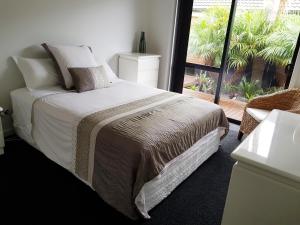 陶朗加Papamoa Retreat的一间卧室设有一张床和一个大窗户