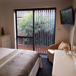 陶朗加Papamoa Retreat的一间卧室设有一张床和一个滑动玻璃门