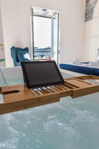 萨莱诺Relais Mareluna - Luxury Apartments的坐在水上木桌旁的笔记本电脑