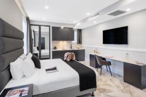 悉尼Holiday Inn & Suites - Parramatta Marsden Street, an IHG Hotel的一间卧室配有一张床、一张书桌和一台电视。