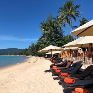 利巴诺伊Kanok Buri Resort的海滩上的一排躺椅和遮阳伞