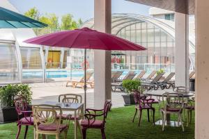 马德里Madrid Airport Suites, Affiliated by Meliá的一个带桌椅和紫色雨伞的庭院