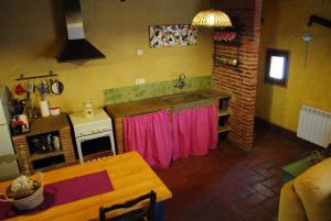 科尔努德利亚Masia El Canalot - Molí Del Pont的厨房配有桌子和带粉红色窗帘的炉灶。