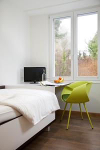 WaldbreitbachRosa Flesch Hotel und Tagungszentrum的一间卧室配有一张床、一张桌子和一把绿色椅子