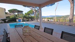 圣马克西姆villa claire de lune la Nartelle的一个带游泳池的庭院里的一张木桌和椅子