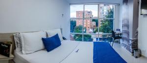 麦德林Hotel Laureles Plaza的窗户客房内的白色床和蓝色枕头