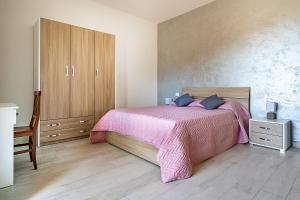 维克艾库塞Villa Russo的一间卧室配有粉红色的床和木制橱柜