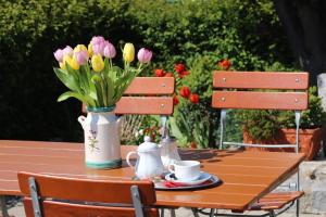 因戈尔施塔特Hotel Hecht Garni的一张木桌,花瓶上是粉红色和黄色的花朵