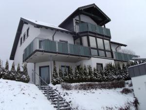 Wiemeringhausen莫斯-霍赫藻厄兰公寓的一座大型白色房子,在雪中设有阳台