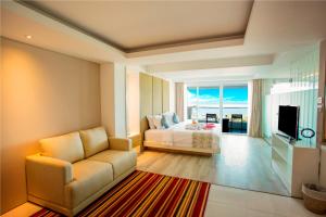 努沙杜瓦Benoa Sea Suites and Villas的一间卧室配有一张床、一张沙发和一台电视