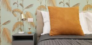 米兰Serendipity Apartments - Duomo的一间卧室配有一张带橙色枕头和棕榈树壁纸的床