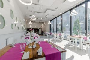 比得哥什依卡酒店的一间设有白色桌子和紫色桌布的用餐室