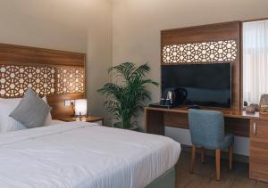 延布فندق جمانة ينبع的一间卧室配有一张床、一张书桌和一台电视