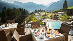 奥蒂塞伊多洛米蒂阿尔比恩山温泉度假酒店的一个带游泳池的阳台上一张带食物盘的桌子