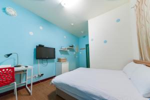 台中市逢甲客居的一间带蓝色墙壁、一张床和电视的卧室
