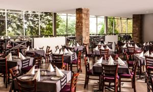 马塞卢Avani Maseru Hotel的用餐室设有桌椅和窗户。