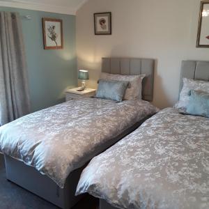 洛斯托夫特Kingsleigh Guest House的一间卧室设有两张床和一张桌子上的台灯。
