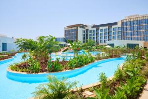 塞拉莱Millennium Resort Salalah的一座拥有树木和建筑的大型游泳池的度假酒店