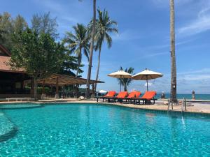 利巴诺伊Kanok Buri Resort的一个带椅子和遮阳伞的游泳池以及大海