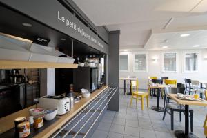 DéolsB&B HOTEL CHATEAUROUX Aéroport的餐厅设有一张带黄椅子和桌子的柜台