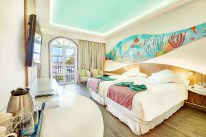 莫甘海滩Hotel LIVVO Puerto de Mogán的酒店客房设有两张床,墙上挂有绘画作品
