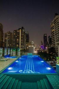 曼谷素坤逸路8号希望之地酒店的一座在晚上拥有城市天际线的大型游泳池