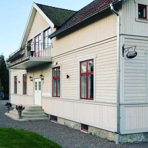 ForsvikVilla Göta的白色的房子,设有红色窗户和阳台