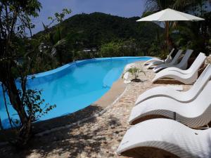 布桑加AL FARO Cosmio Hotel Palawan的一个带白色椅子和遮阳伞的游泳池