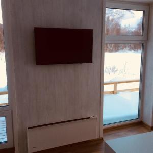 Vang I ValdresMjøsvang Kafe的两扇窗户旁的墙上有一台平面电视