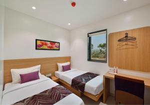 孟买Hotel Leafio-Near Airport的客房设有两张床、一张桌子和一个窗户。