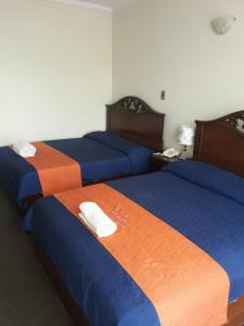 波托西图克斯拉皇家金堡旅馆的一间设有三张床的客房,配有蓝色和橙色