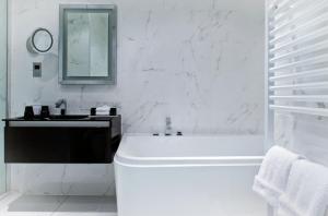 斯特灵科勒西奥酒店的白色的浴室设有浴缸和水槽。
