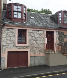 罗撒西Old Fisherman's Cottage的石头房子,设有车库和2个窗户