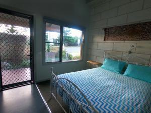 坎贝尔港坎贝尔港弗拉什帕克旅馆的一间卧室配有一张带蓝色床单的床和一扇窗户。