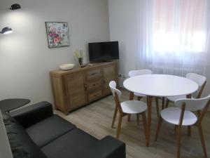 的里雅斯特玫瑰公寓的客厅配有白色桌子和电视