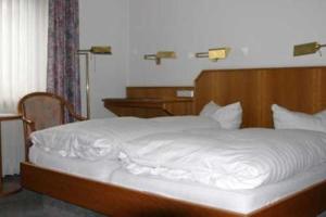 乌尔里希施泰因里斯托兰特艾特纳酒店的一张带木制床头板和白色床单的床