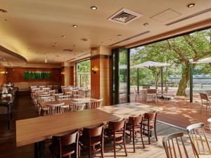 广岛The Royal Park Hotel Hiroshima Riverside的餐厅设有木桌和椅子以及大窗户。