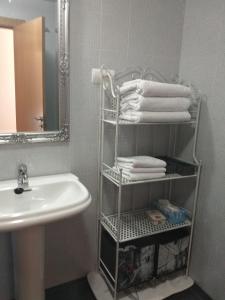 莱昂Apartamento Conde Luna的浴室设有水槽和带毛巾的架子。