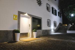 里斯本4U Lisbon VI Guesthouse Airport的前方有两株盆栽植物的建筑物的门