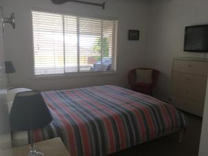 尼尔森湾图莫瑞公寓的一间卧室配有一张带条纹毯子的床和窗户