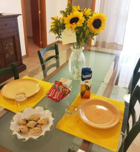 孔韦尔萨诺La villa nel verde的餐桌,餐桌上放着食物盘子,花瓶上放着鲜花